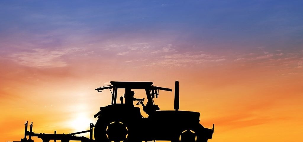 Tractor in field carrying out agric mechanization while the sun sets